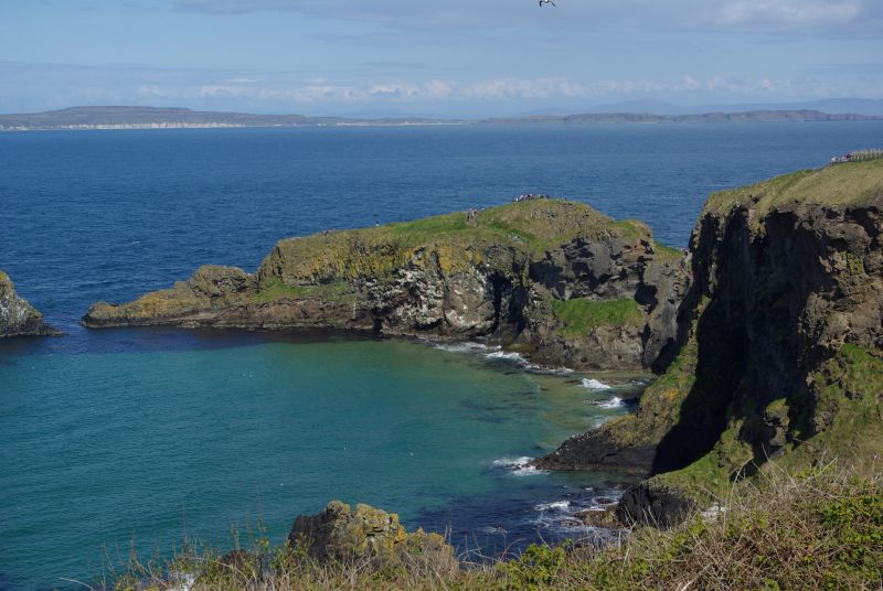 Die Steilküste Irlands in der Sonne mit Blick auf die mit Moos bewachsenen Felsen und das blaue Meer.